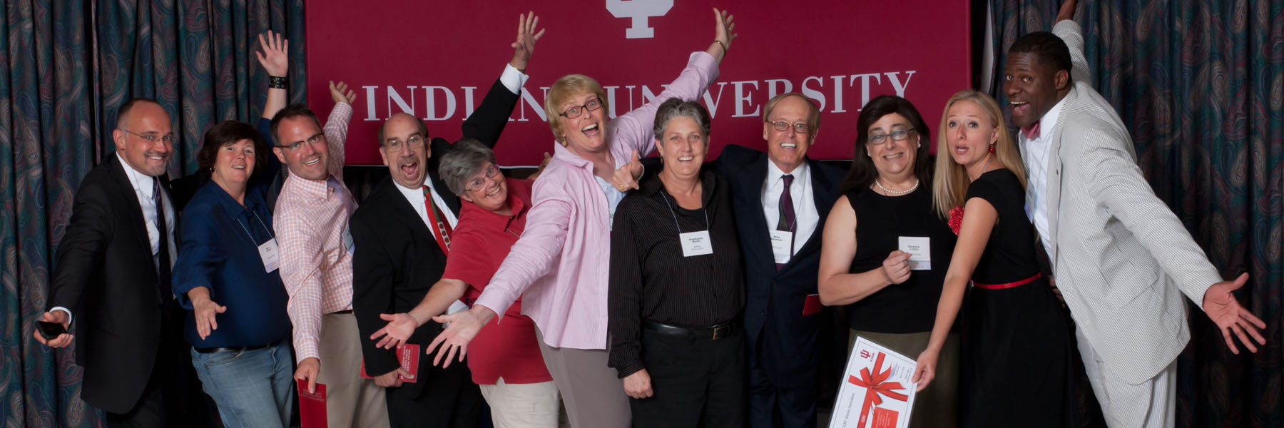 Group of smiling people pose in front of an IU banner.
